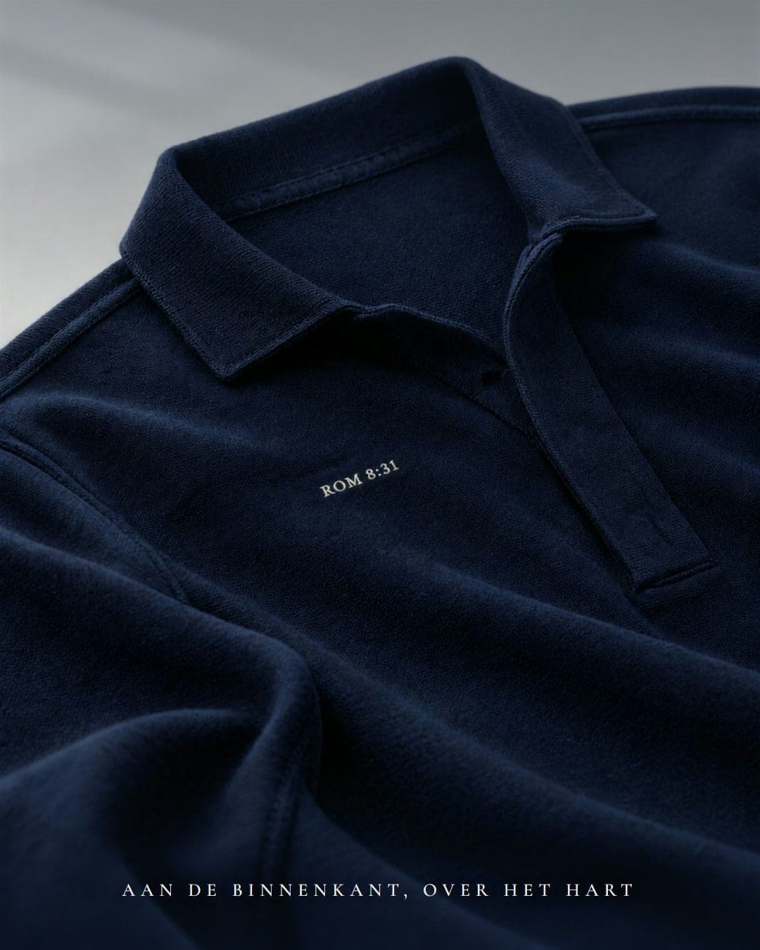 De binnenkant van een navy polo met ROM 8:31 ter hoogte van het hart.